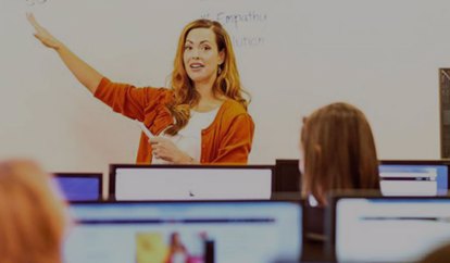 Colleague Stood In Front Of A Class Gesturing To A Whiteboard