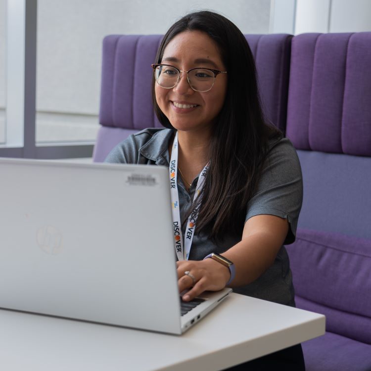 Discover employee with glasses working on her laptop in a booth