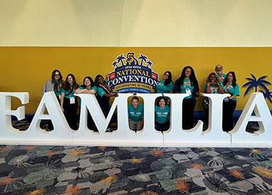 Discover Employees Posing for a Group Photo in front of a FAMILIA sign